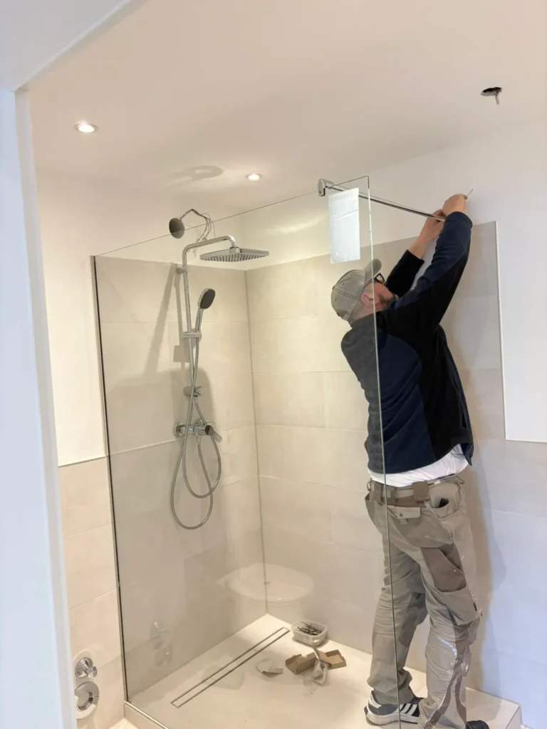Monteur installiert eine bodengleiche Dusche mit Glaswand